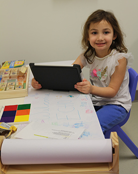 girl holding tablet sitting at table