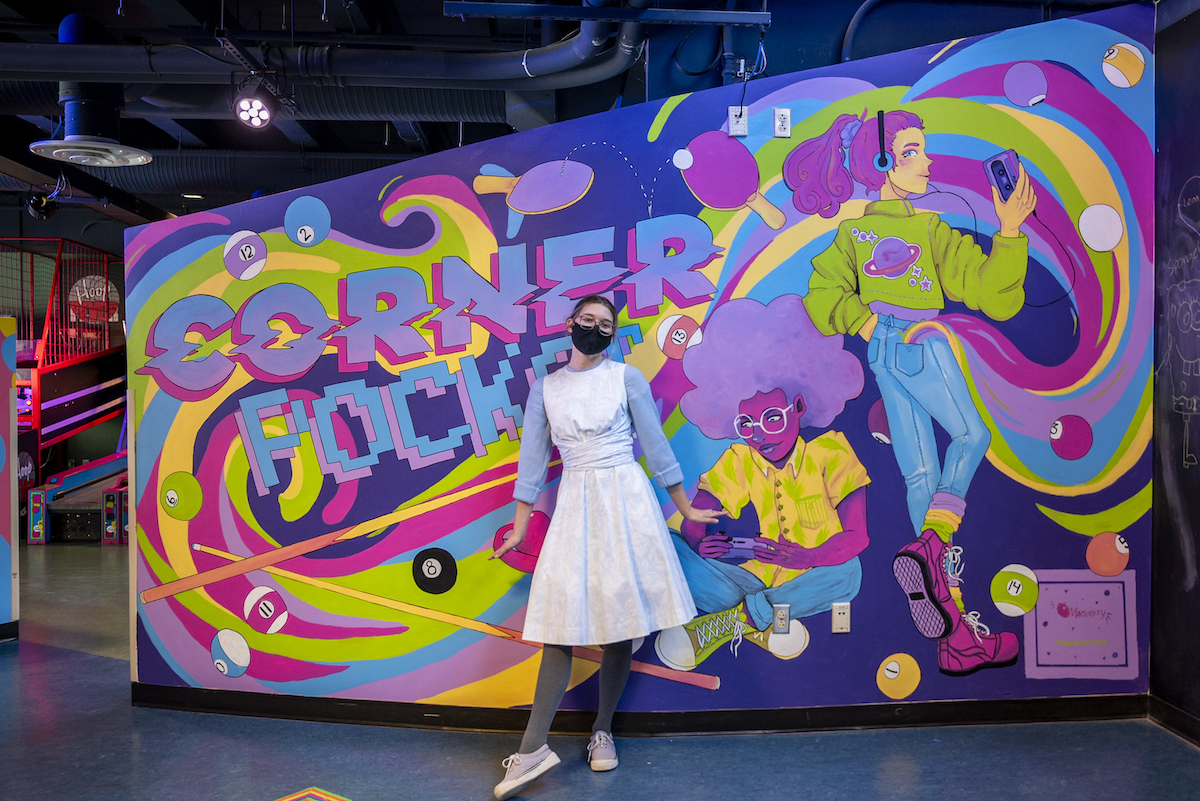 woman artist poses with her mural