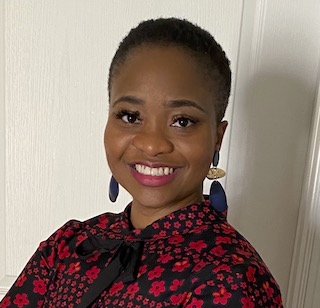 Law student Chinyelum (Chi-Chi) Olele smiles at the camera. She is wearing a red and black shirt and large earrings.