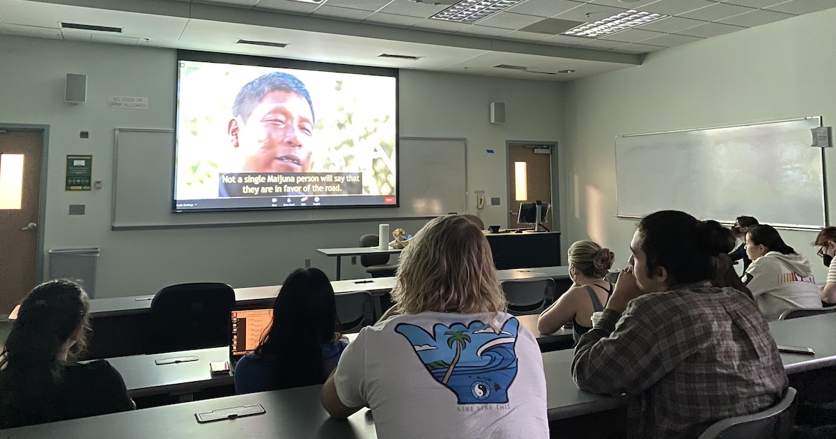 students in a room watching a film on a screen