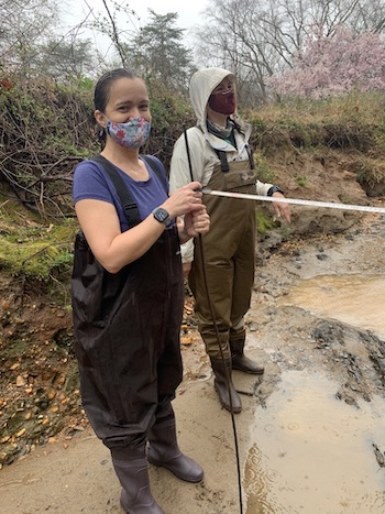 two people standing in hip waders in the rain