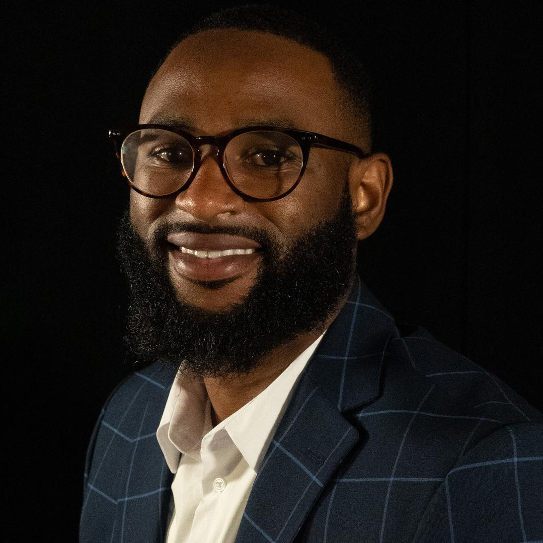 Dovan "Ace" Willis in a blue suit jacket, yellow shirt, and glasses.