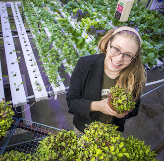 woman holding a plant in a greenhouse