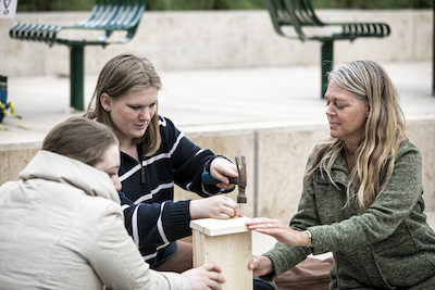 three woman work on a wooden structure