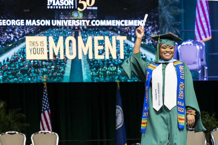 graduate on stage holding a scroll