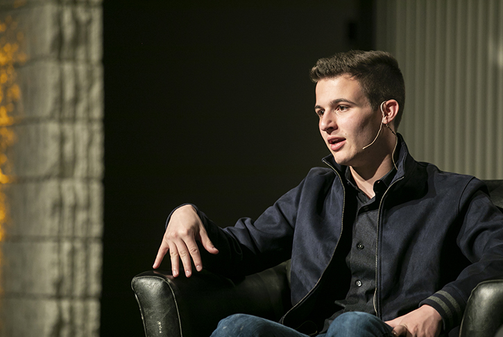 Cameron Kasky sitting in a chair on stage and speaking to the audience.