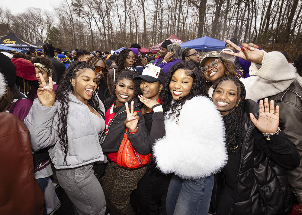 Six female students hold up the peace sign during homecoming tailgate party.