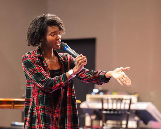 Jneva Norfleet speaks to a crowd with her hand outstretched, holding a microphone