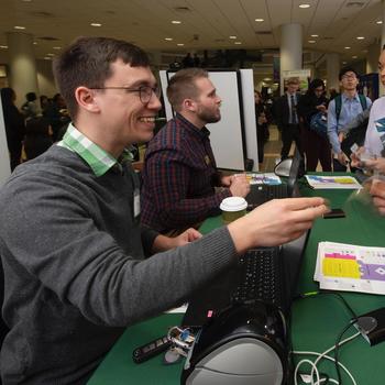 Two Mason GAPSA students sitting at a table with a green tablecloth at Mason Career Fair.